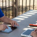 un aveugle utilisant son Braille Sense U2 Azerty en face d’un collègue avec une tablette